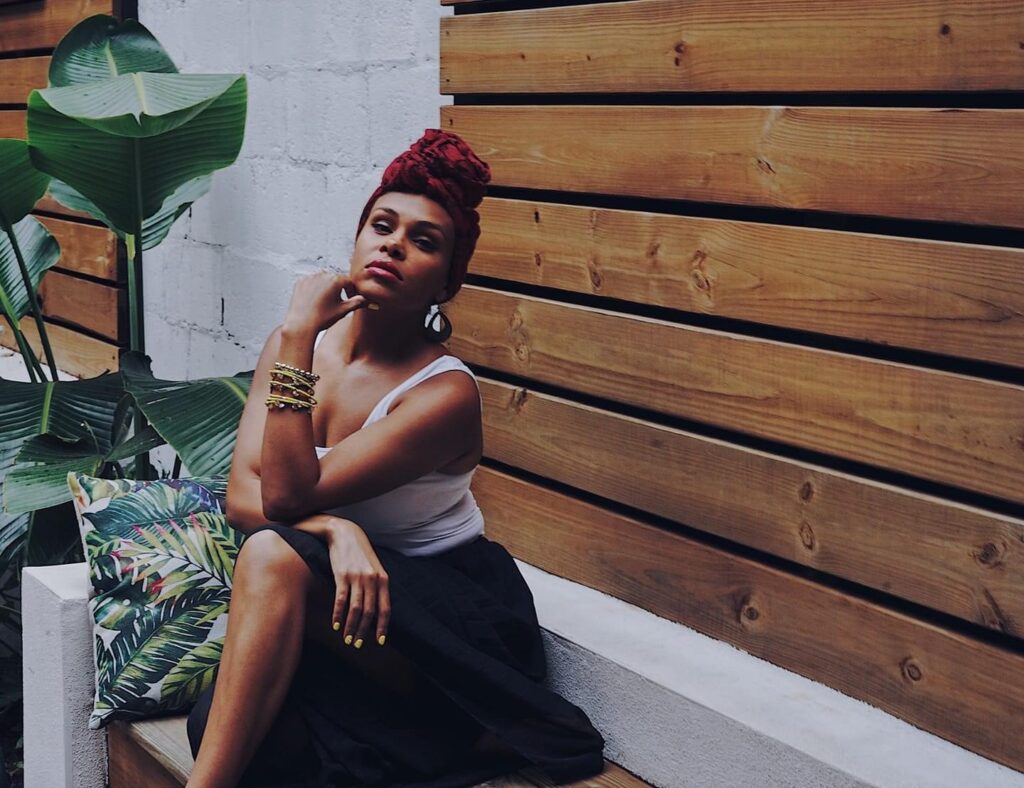 Tiffiny Williams sitting on a bench with wood panel background.